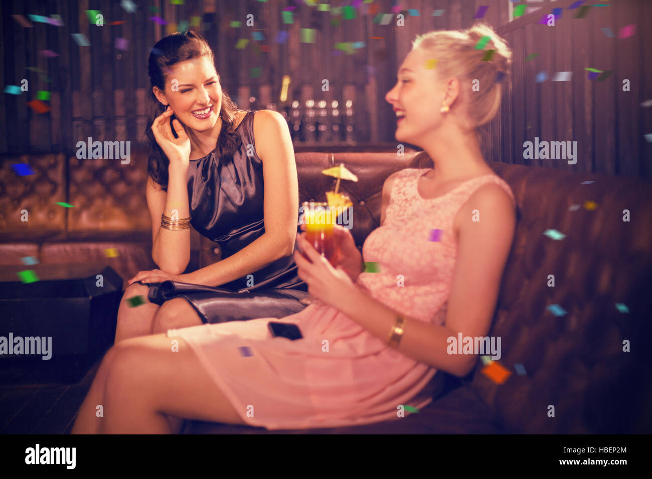 Composite image of female friends interacting with each other while having cocktail Stock Photo