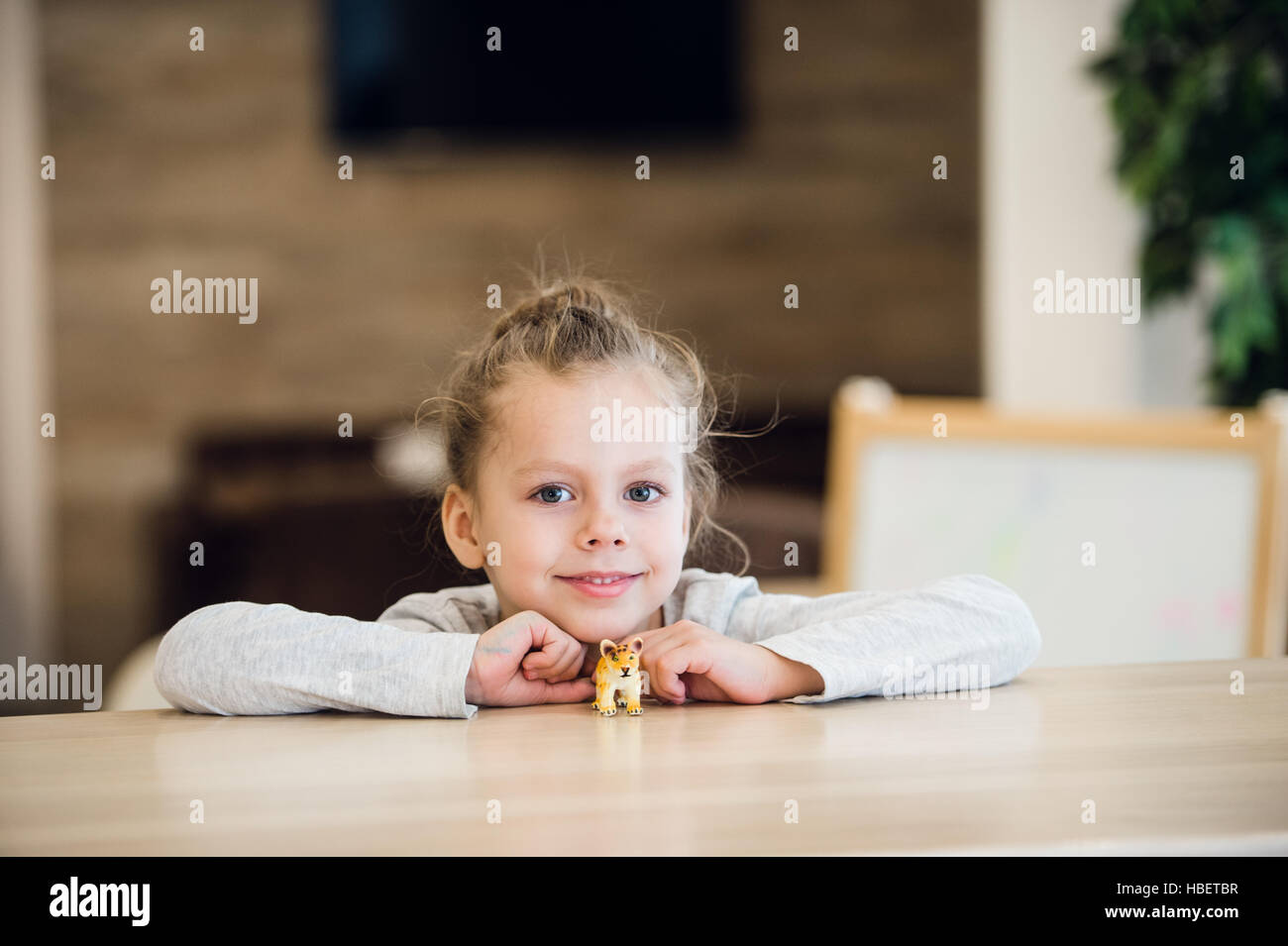 Beautiful calm little girl sitting at wooden table Stock Photo - Alamy