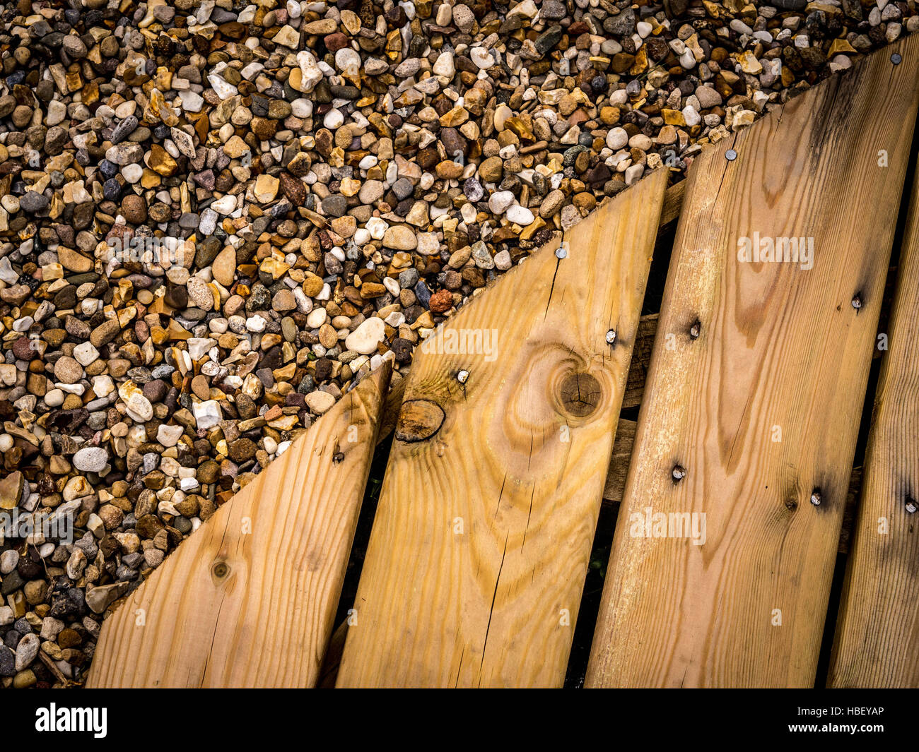 Edge of circular decking area in garden set within gravel Stock Photo
