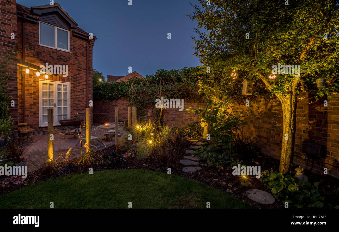 Modern garden design at dusk with contemporary upcycled shopping trolley chairs for seating and large Kadai firebowl. UK Stock Photo
