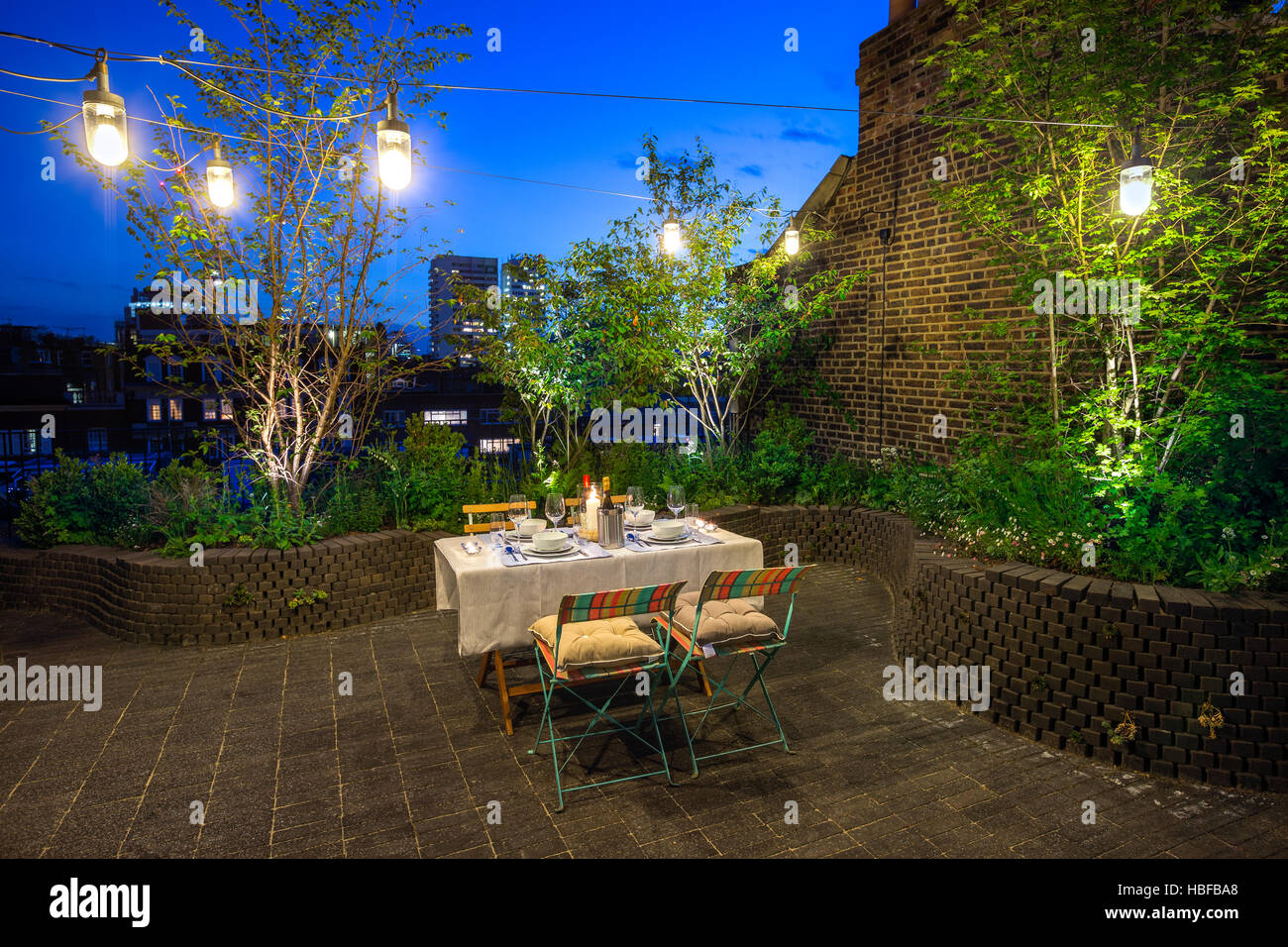 Roof terrace design with traditional brick pavers surfacem, raised beds, lush planting and beautiful garden lighting Stock Photo