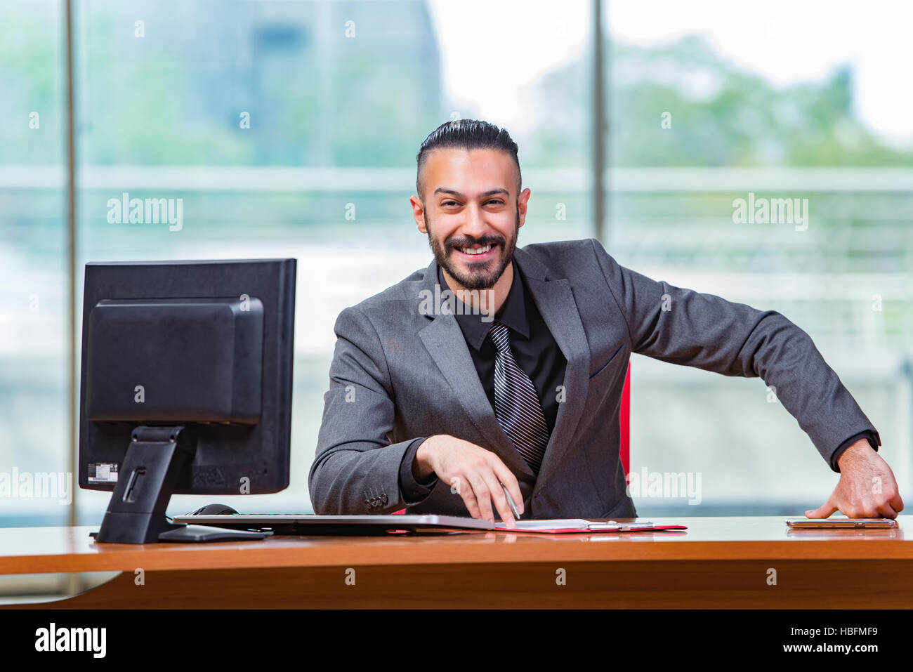 Happy businessman sitting at the desk Stock Photo - Alamy