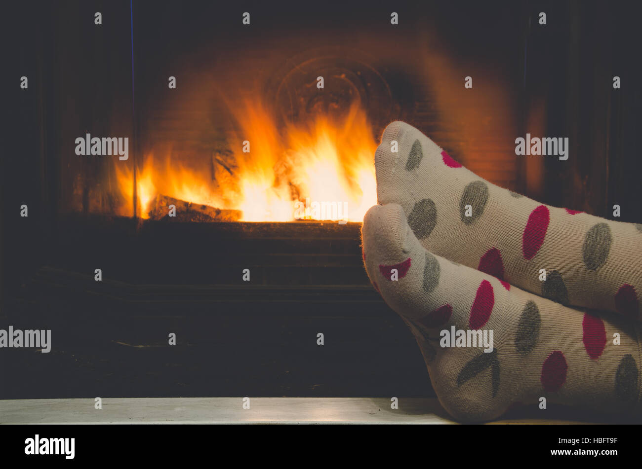 Feet in socks of all the family relaxing and warming by cozy fire Stock Photo