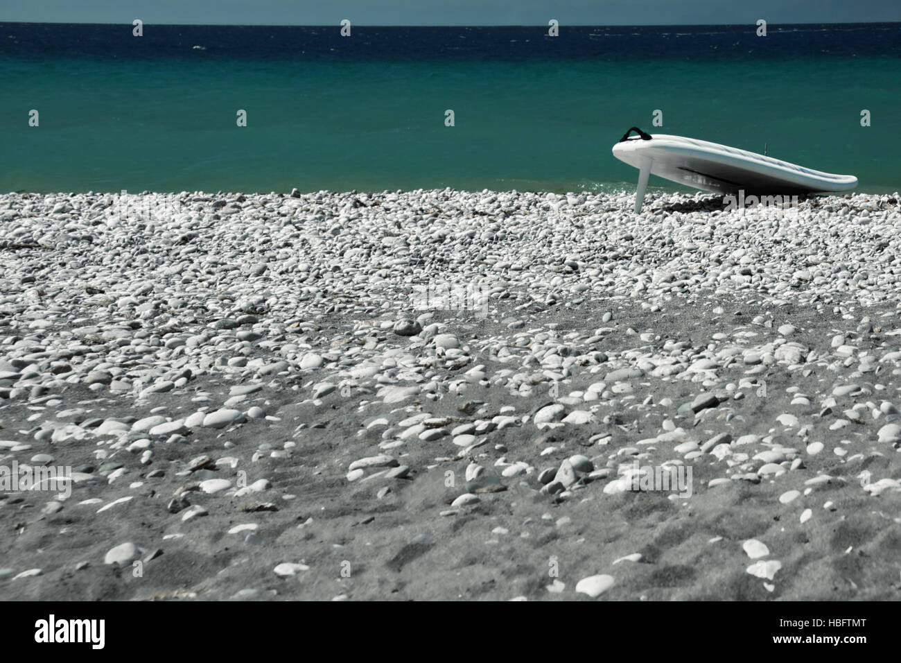 Surfboard on a pebble beach Stock Photo