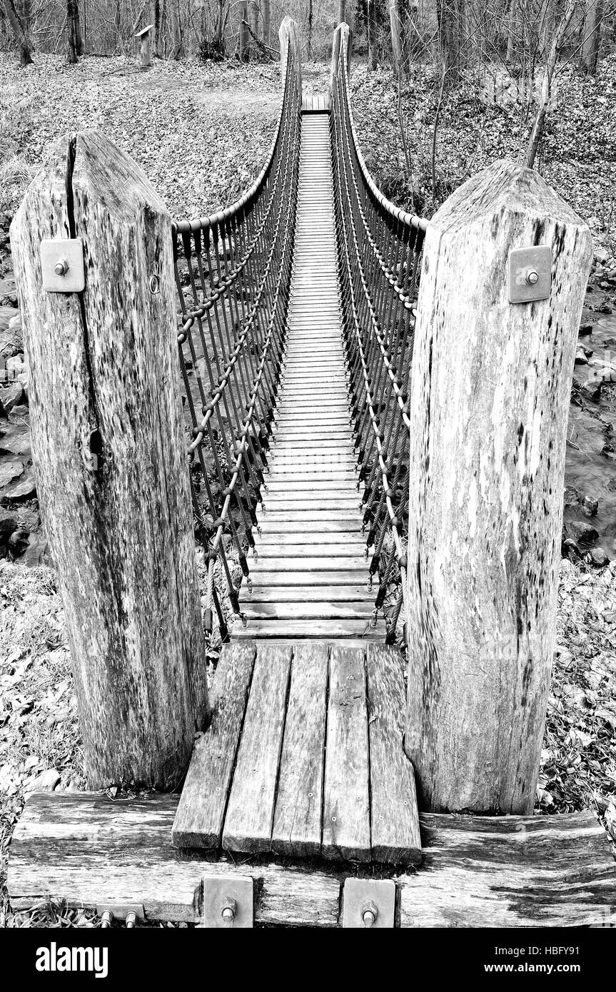 Suspension bridge over the creek black-white Stock Photo