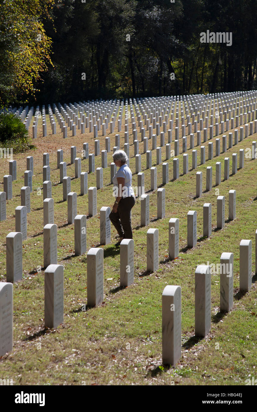 Woman Walking Through Headstones In National Veterans Cemetery Woman Walking Through Headstones In National Veterans Cemetery