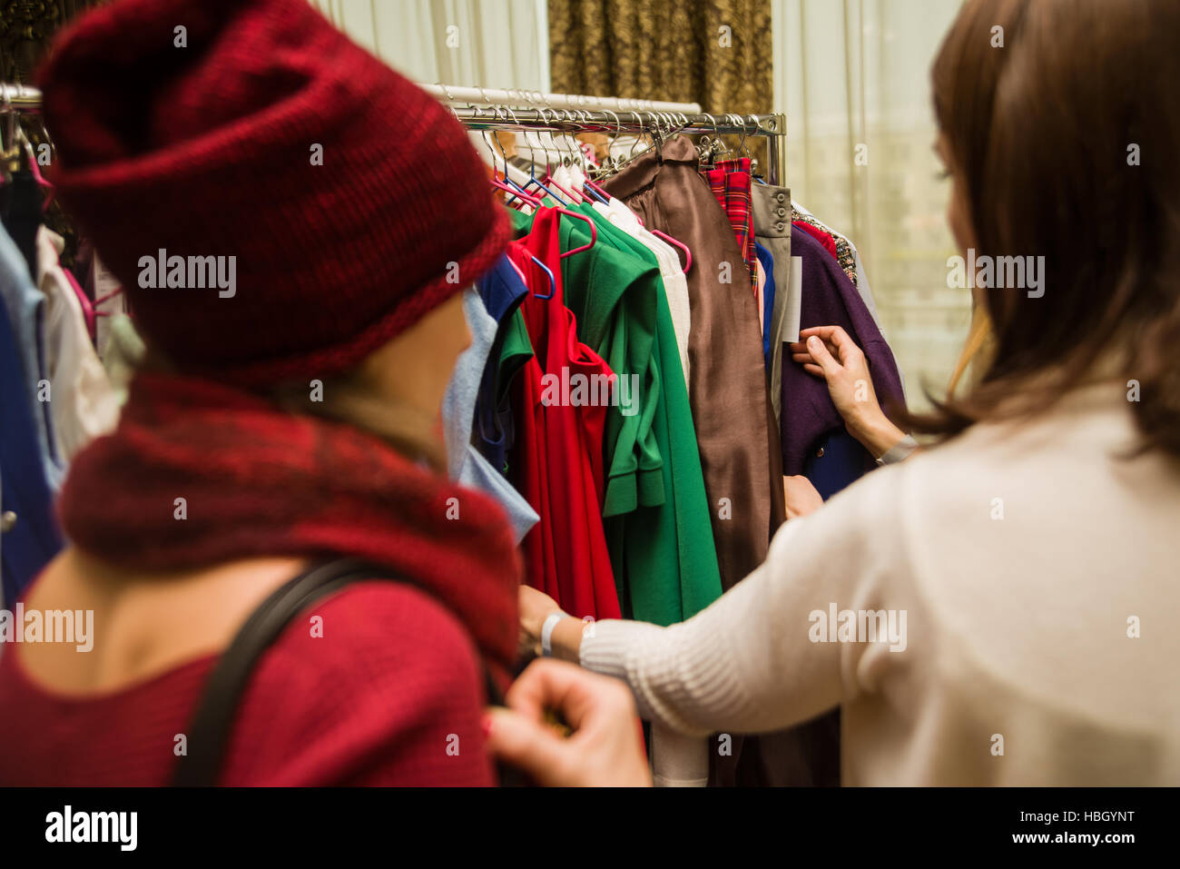 Group of young beautiful women shopping in fashion mall, choosing new clothes, looking through hangers with different casual colorful garments on hang Stock Photo