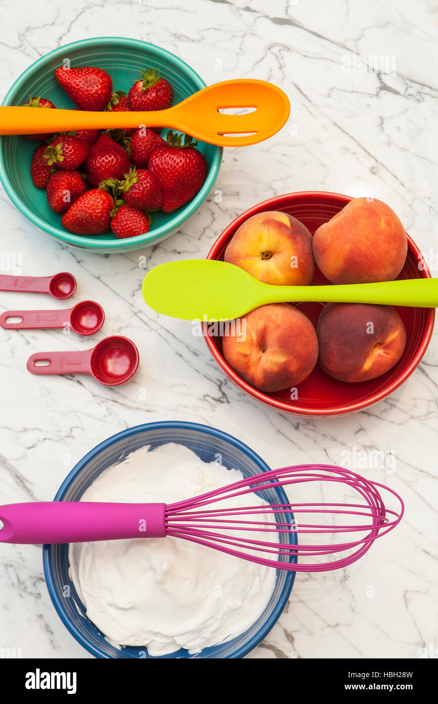 colorful kitchenware and bowls with strawberries, peaches and cream