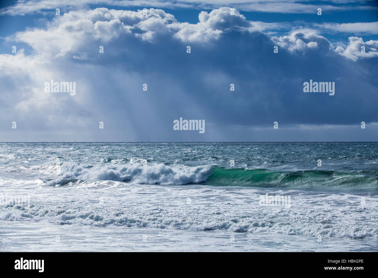 storm surf and rain clouds with rays of sunlight poking through, Hendry's Beach, Santa Barbara, California Stock Photo