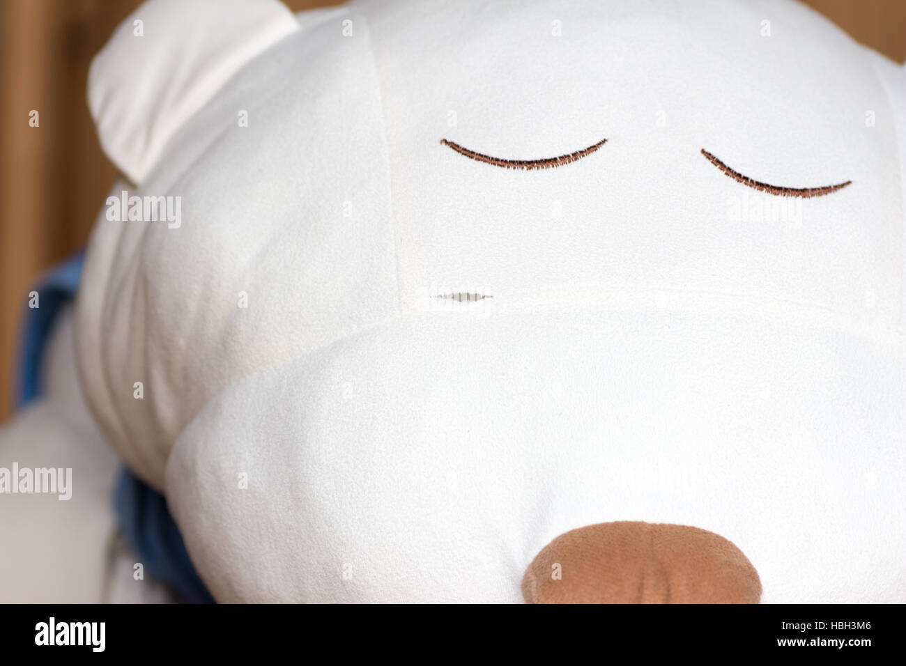 A little rip, ripped, torn, on the face of a white sleeping stuffed bear Stock Photo