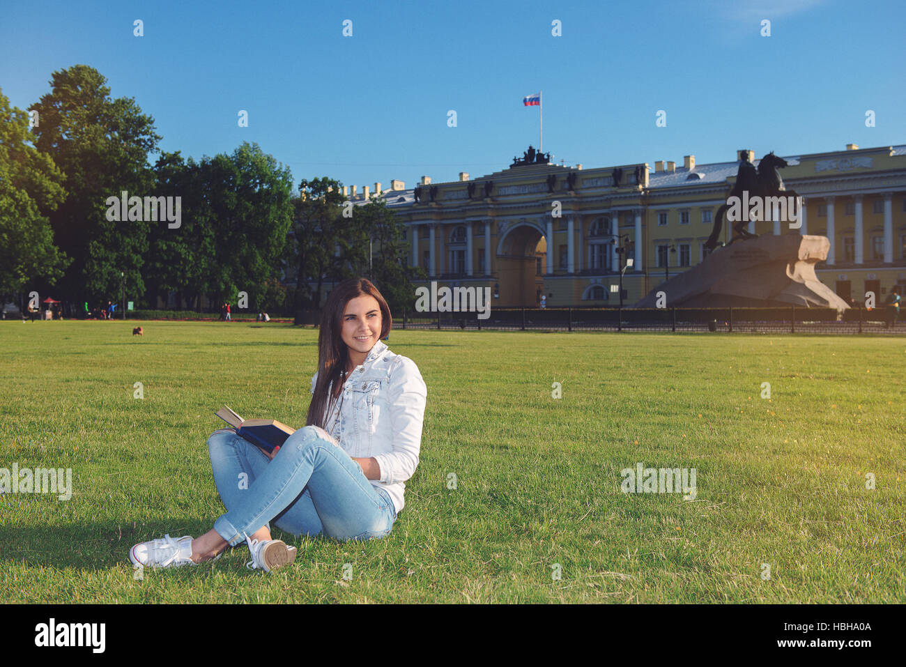 Girl-student sit on lawn and reads textbook Stock Photo - Alamy