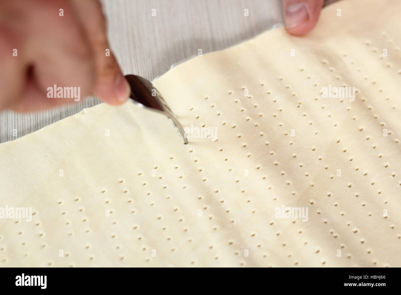Pricking puff pastry sheet with fork. Making Pear Tarte Tatin with Cardamom series Stock Photo