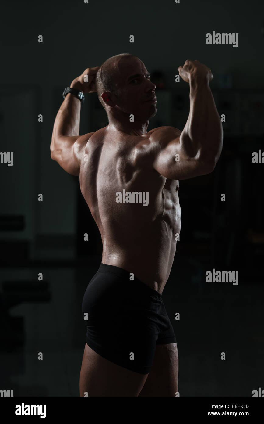 Muscular athletic bodybuilder fitness model posing after exercises in gym  Stock Photo