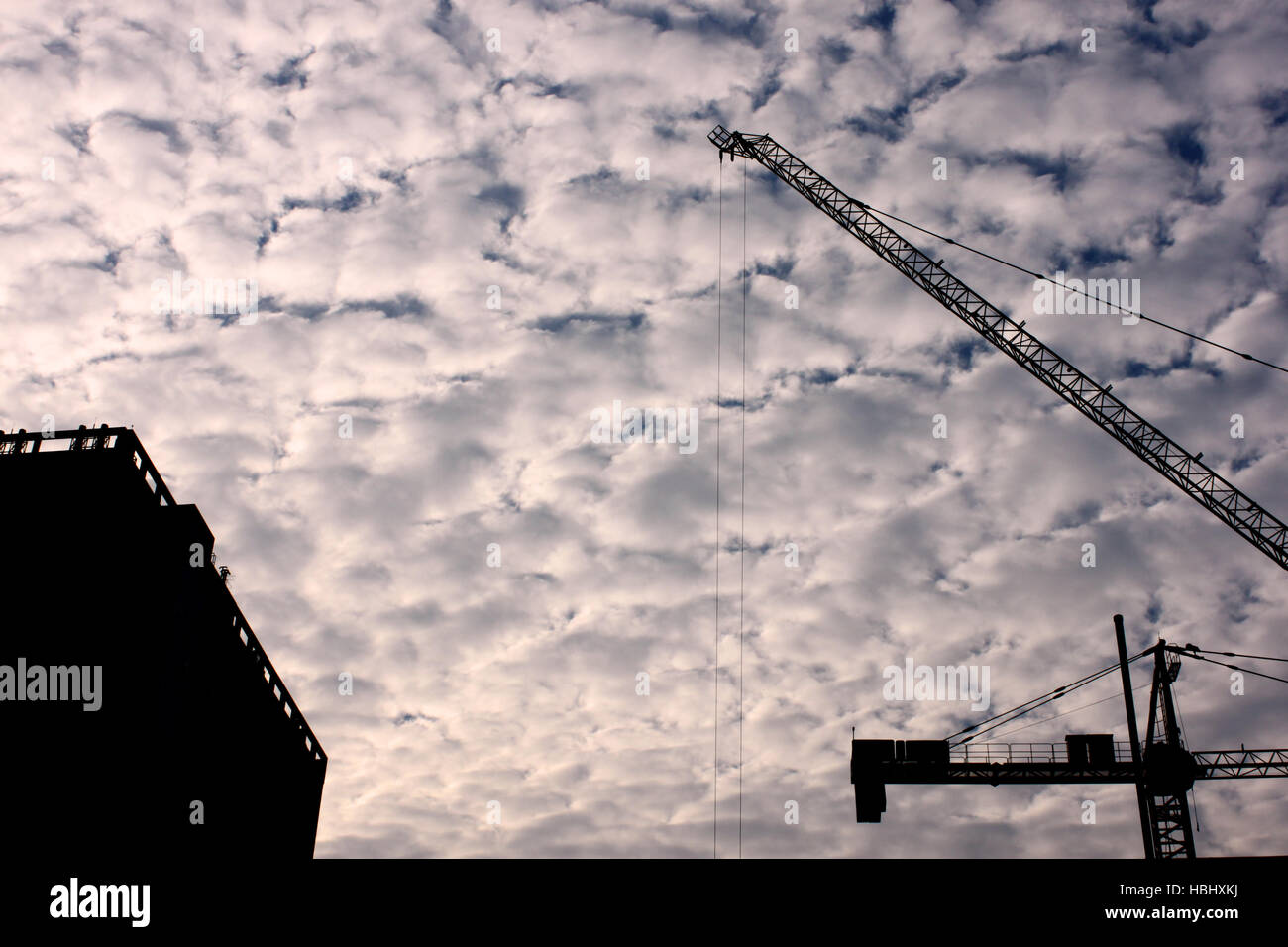 A crane is silhouetted against the sky at a construction site in Chulalongkorn University, Bangkok, Thailand. Stock Photo