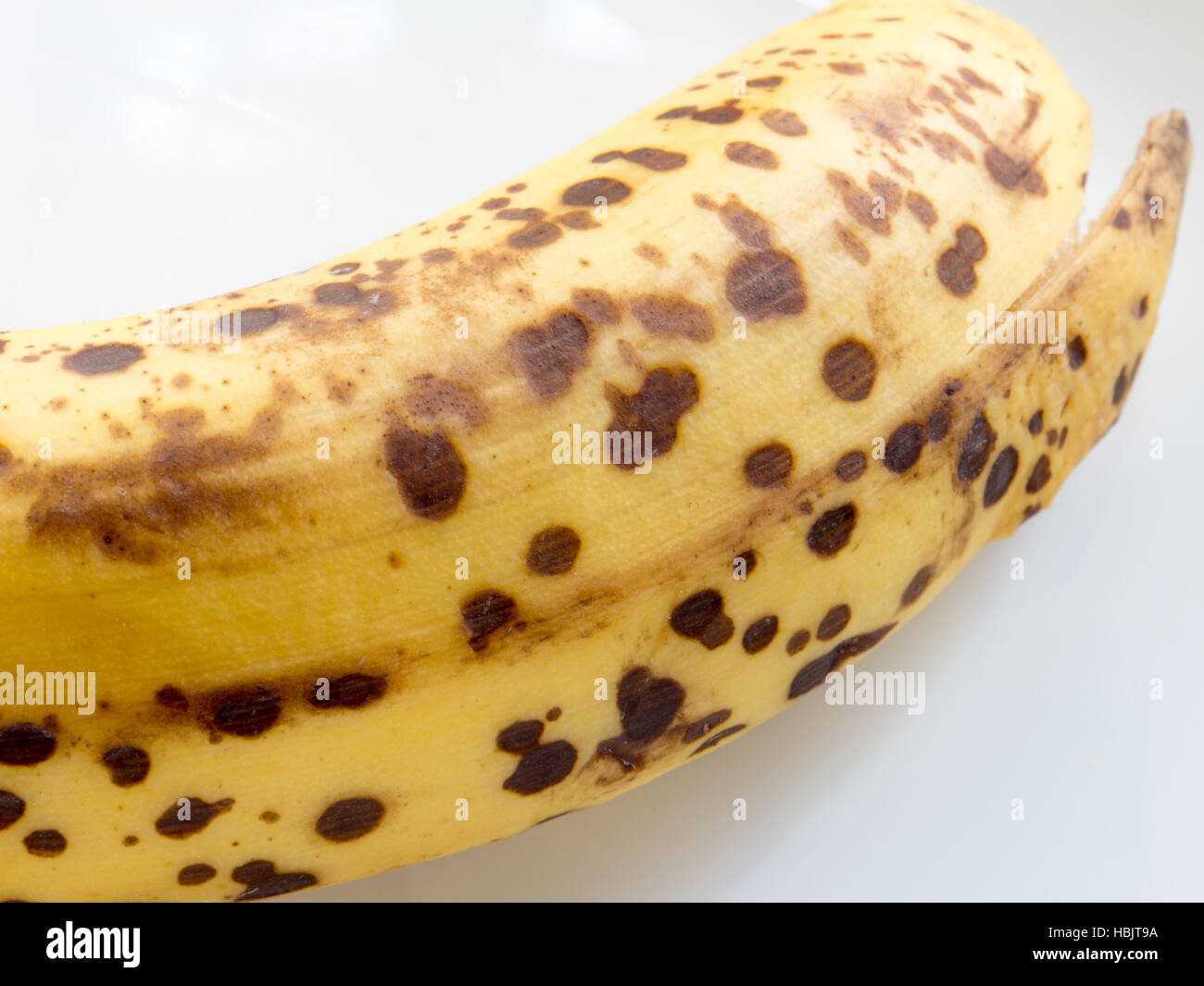 Well ripe banana with black spots on white isolated background Stock Photo