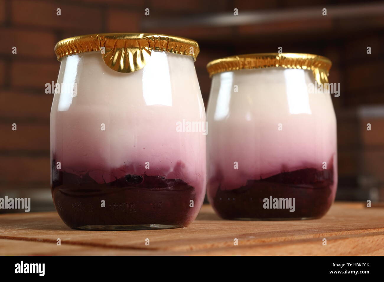 Yogurt with jam in small glass jar with aluminium foil seal cap. Macro