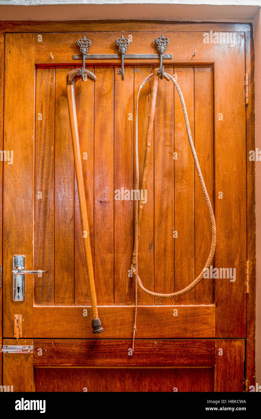 Whip and walking stick behind door Stock Photo