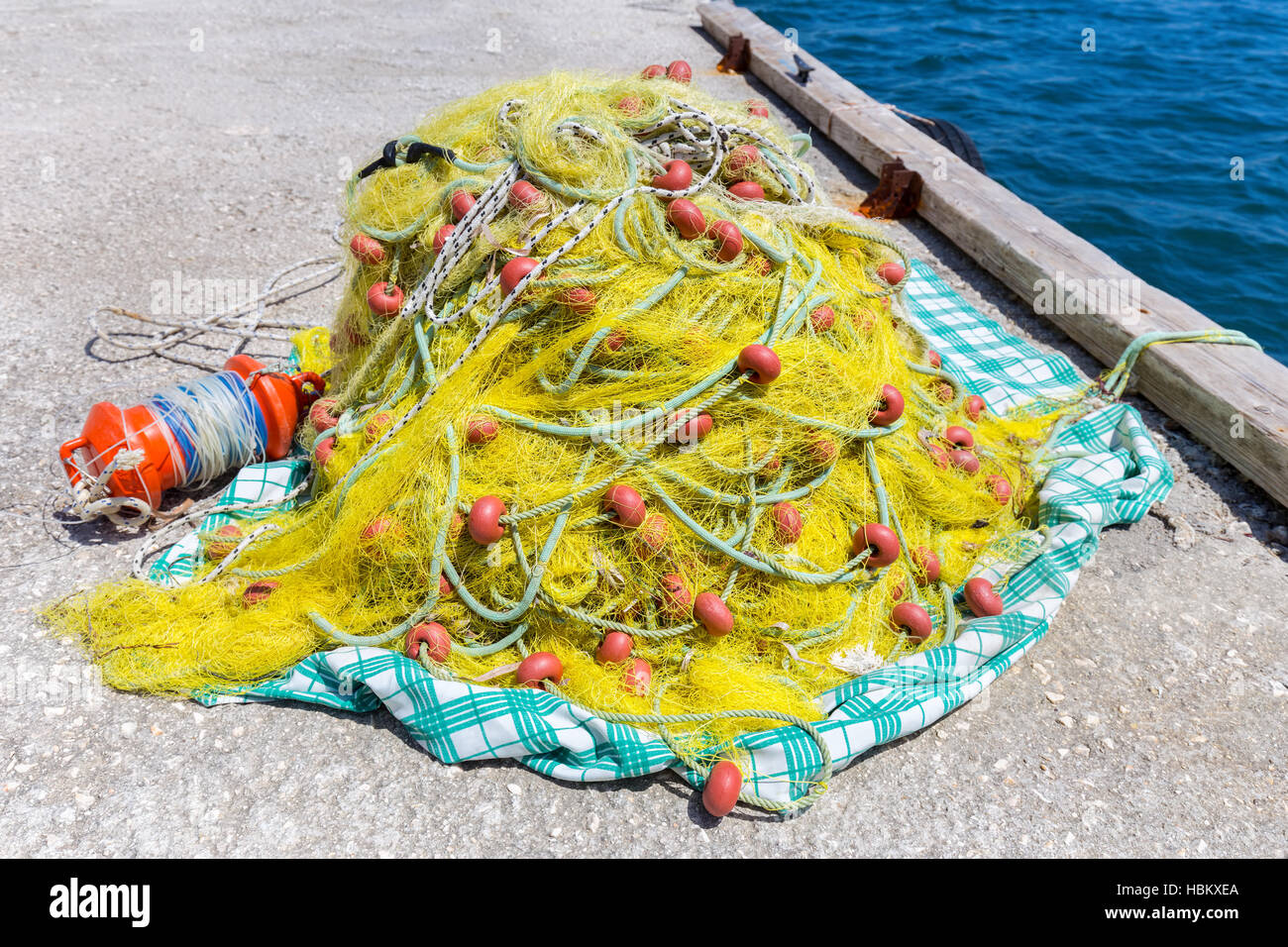 Heap of yellow fishnet on ground at sea Stock Photo
