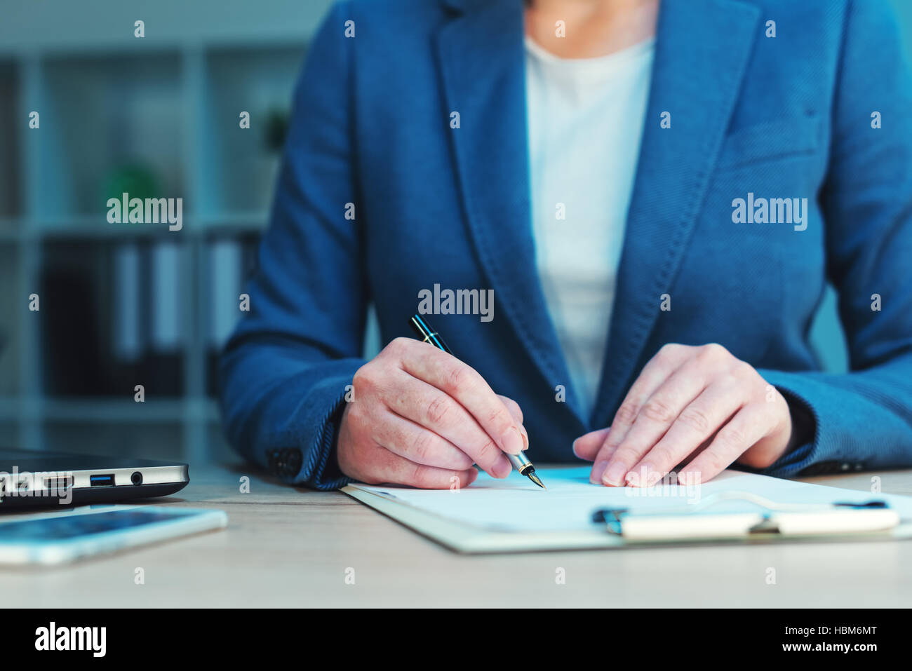 Business agreement signing, businesswoman handwriting signature on contract document at office desk Stock Photo