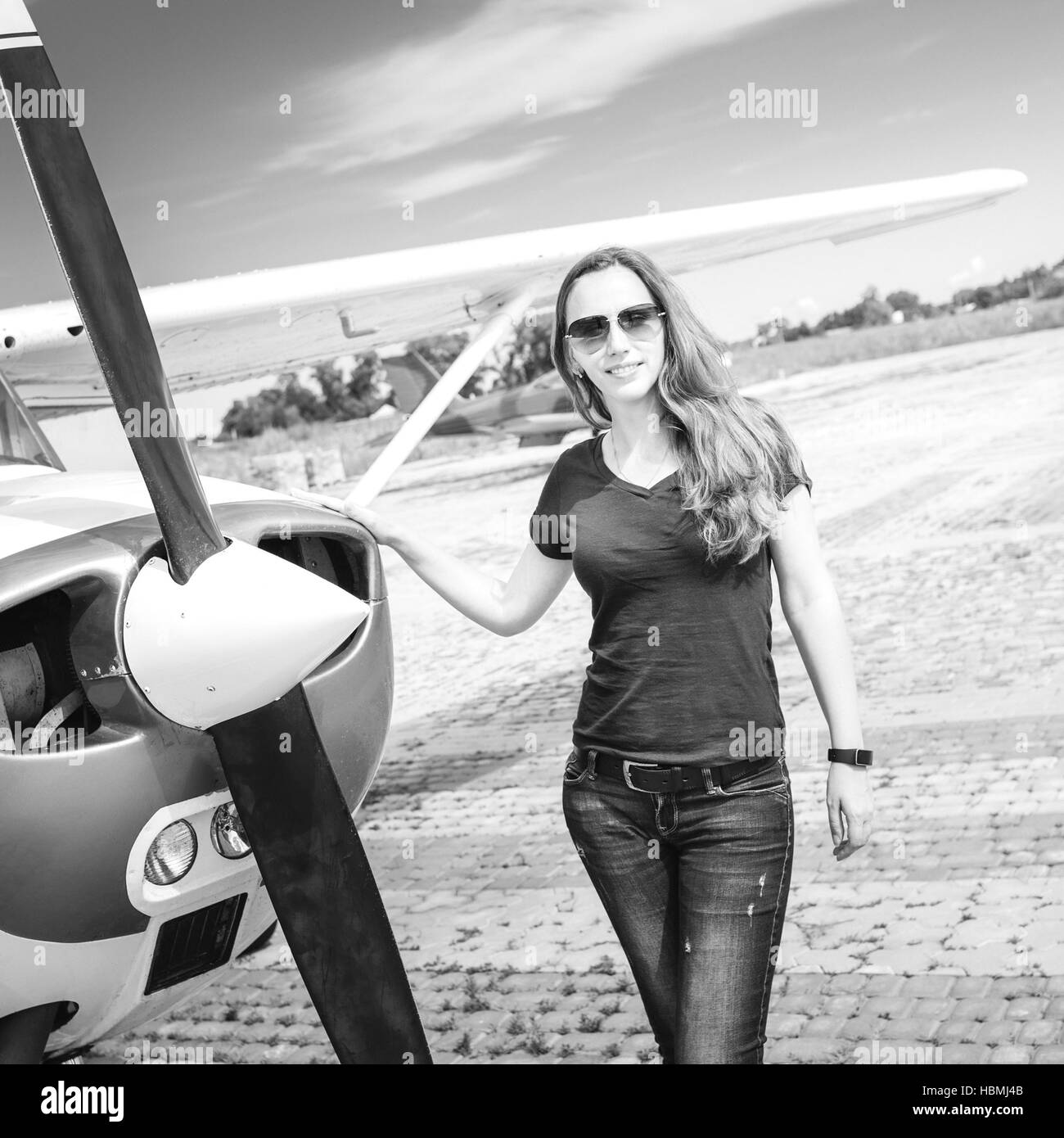 Young smiling woman standing near private plane ready for flight Stock Photo