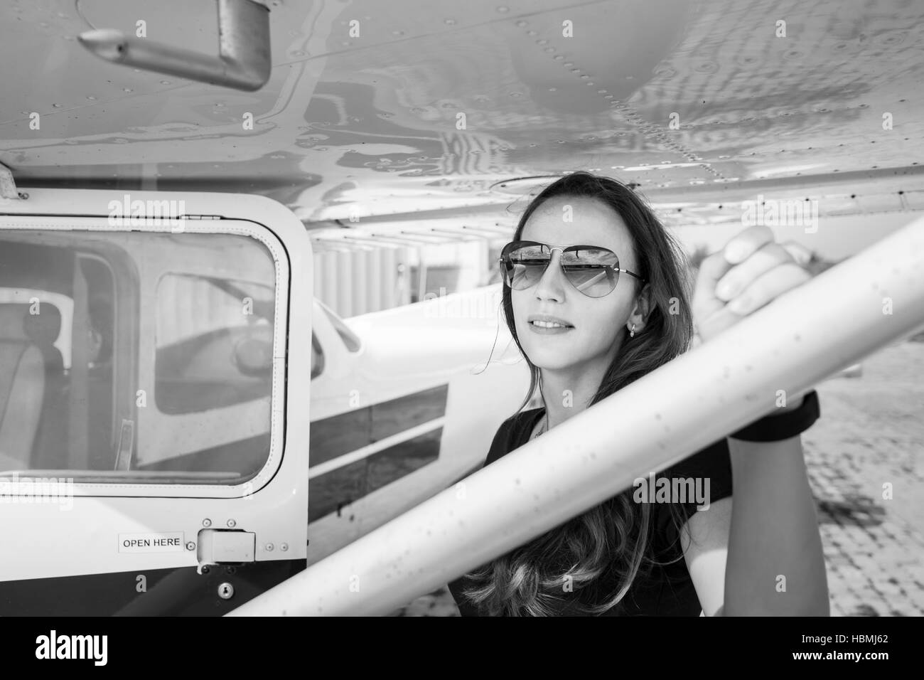 Young smiling woman standing near private plane ready for flight Stock Photo