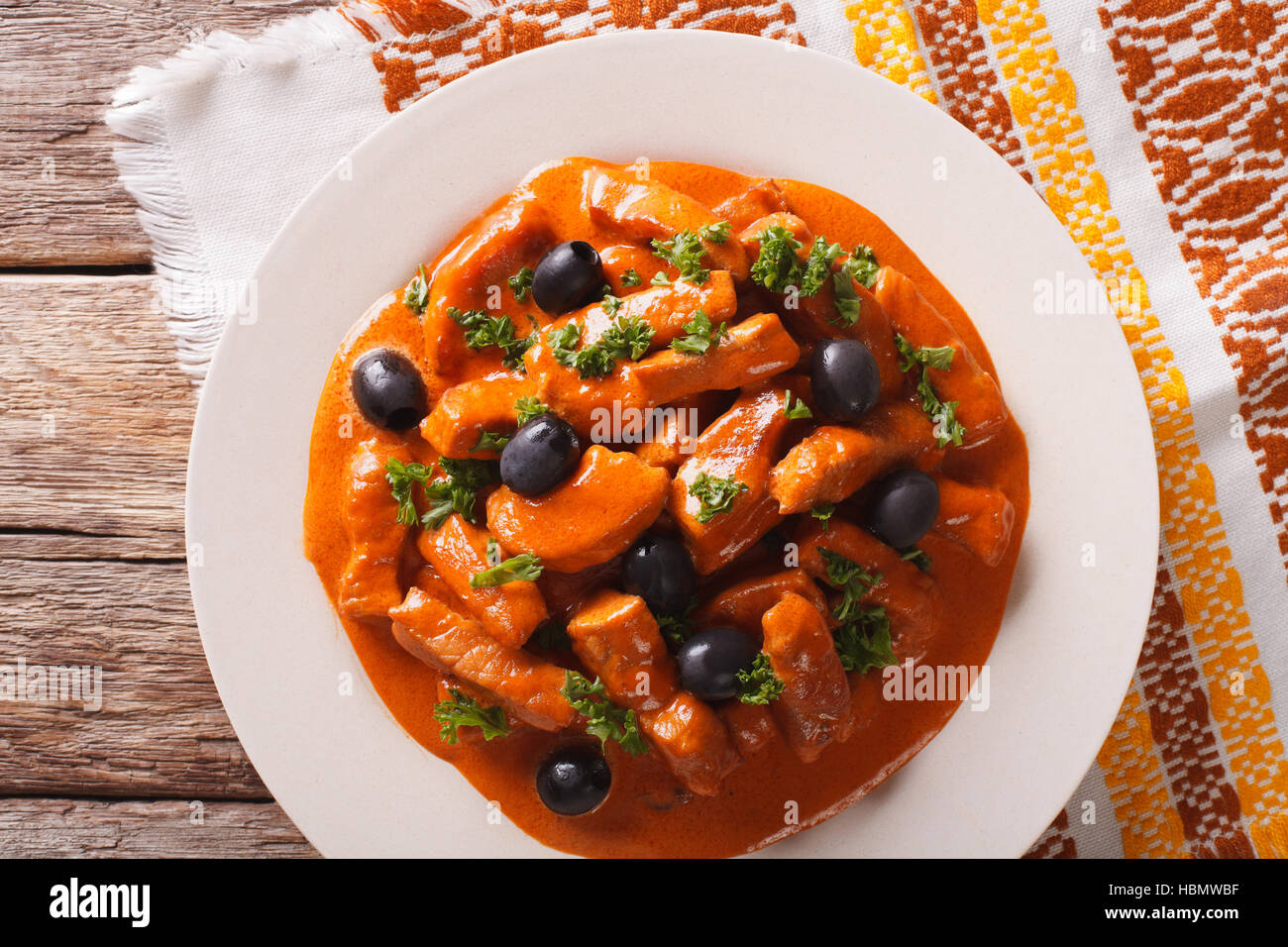 pork stew in a spicy sauce of wine, tomatoes and cream with black olives close-up on a plate. horizontal view from above Stock Photo