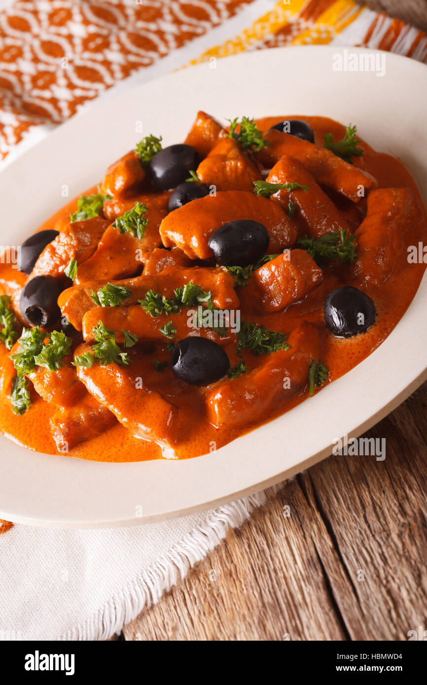 Spanish Food: pork Raxo in a sauce of wine, tomatoes and cream with black olives close-up on a plate. vertical Stock Photo