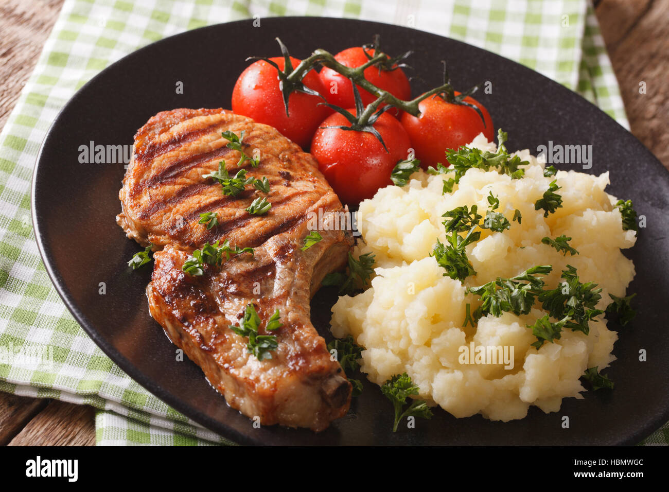 Grilled pork steak with garnish mashed potatoes and tomatoes closeup