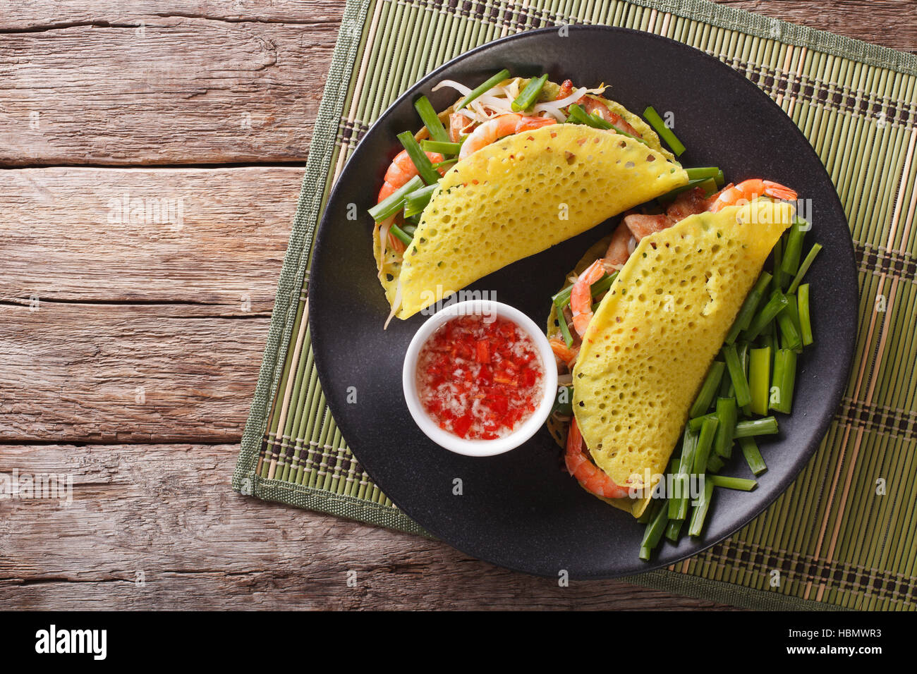 Vietnamese Banh Xeo crepes stuffed with pork, shrimp, onions and bean sprouts and a spicy sauce closeup on a plate on the table. Horizontal view from Stock Photo