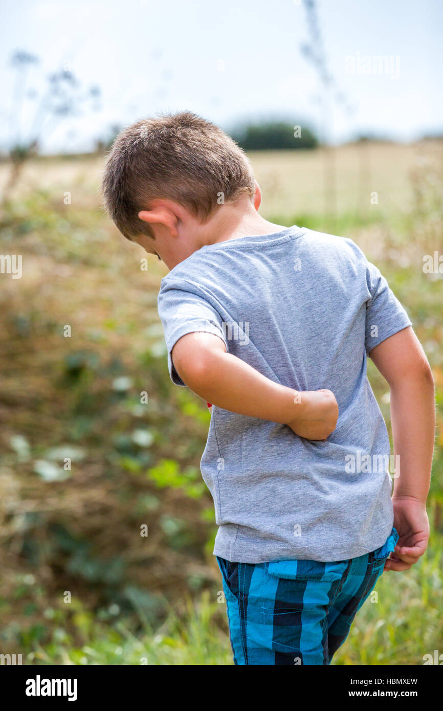child scratching his back on a country road Stock Photo Alamy