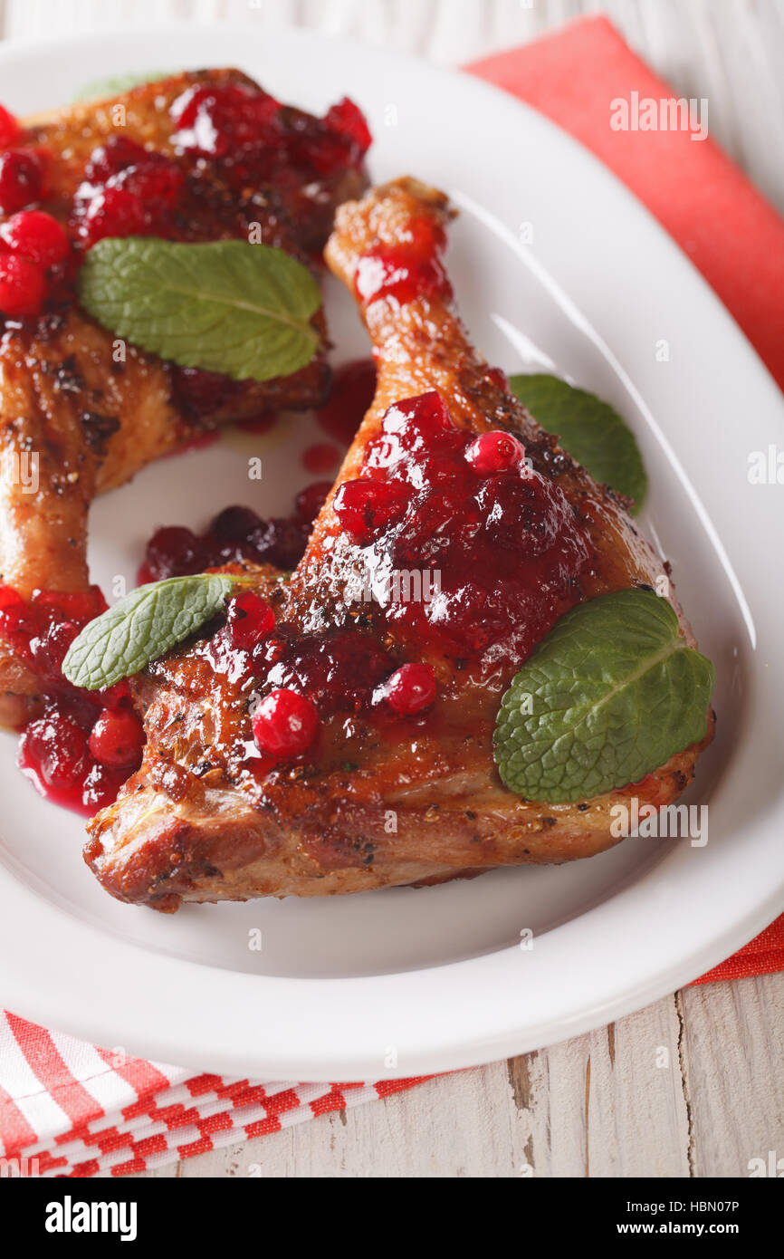Festive food: baked duck leg with cranberry sauce and mint closeup on a