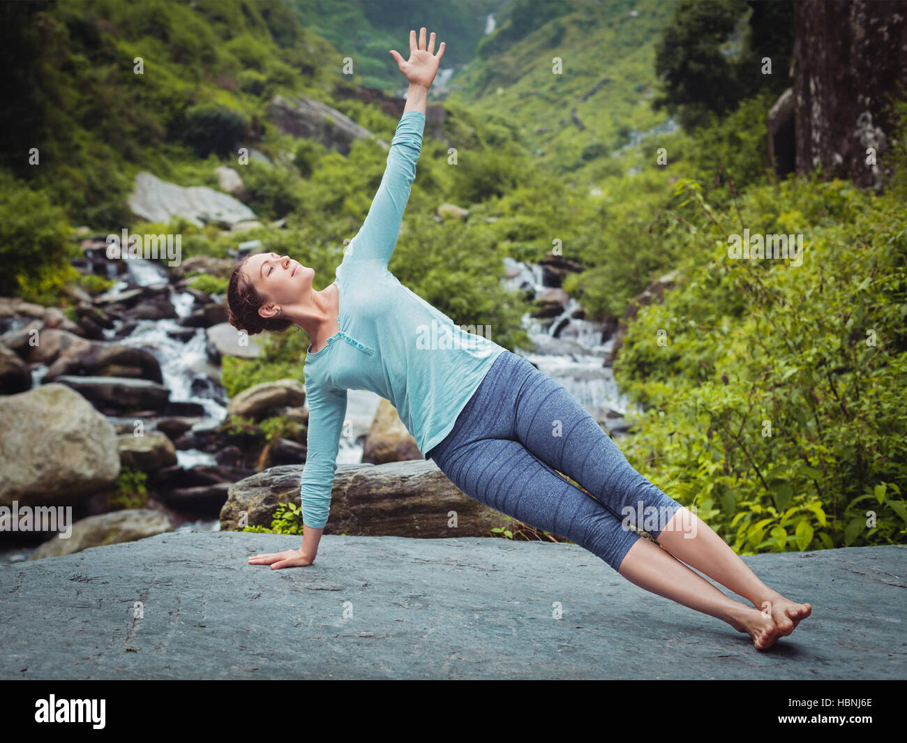 Woman doing yoga asana Vasisthasana - side plank pose outdoors Stock Photo