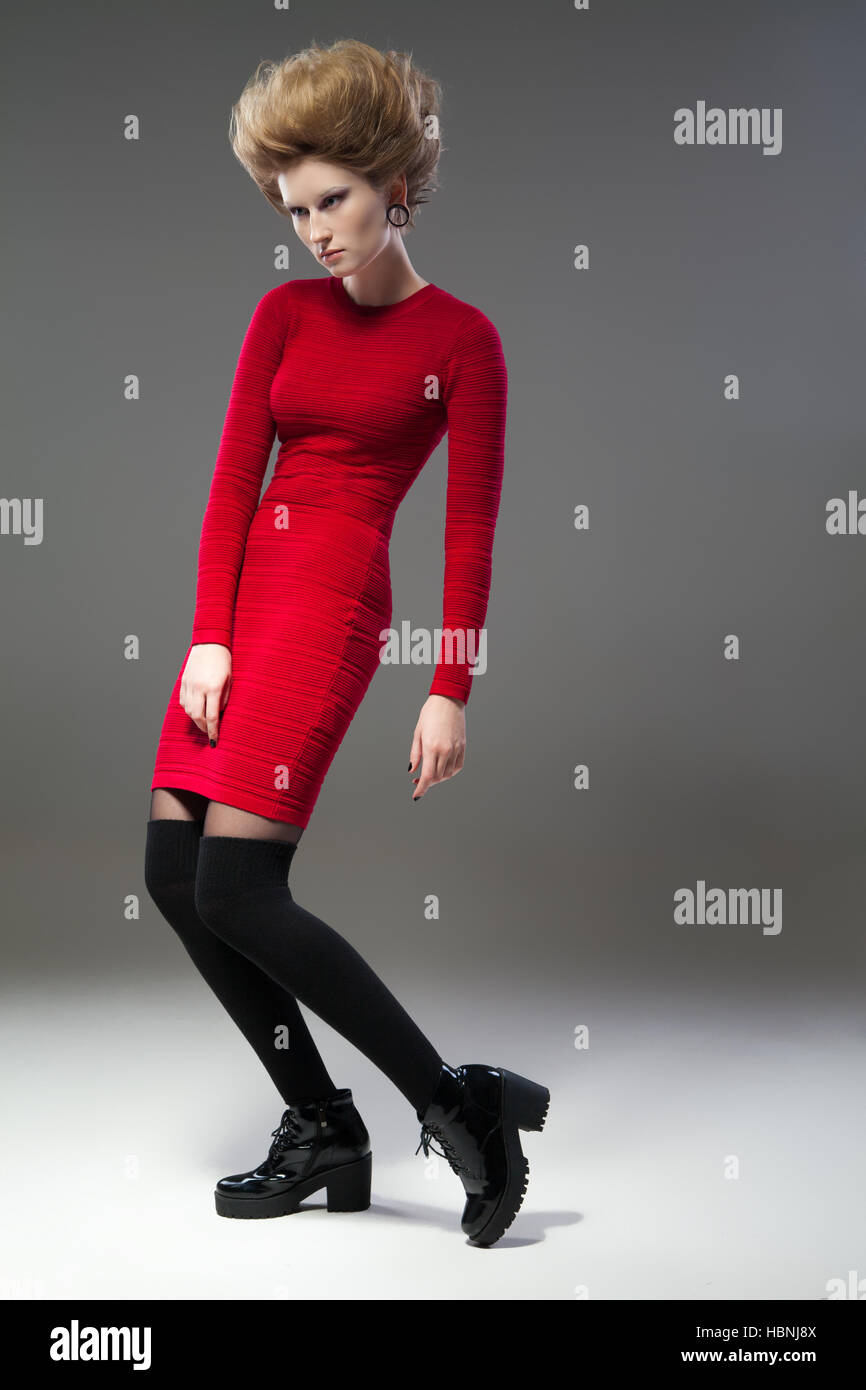 Young female model in red dress, black stocks and boots with hairstyle ...
