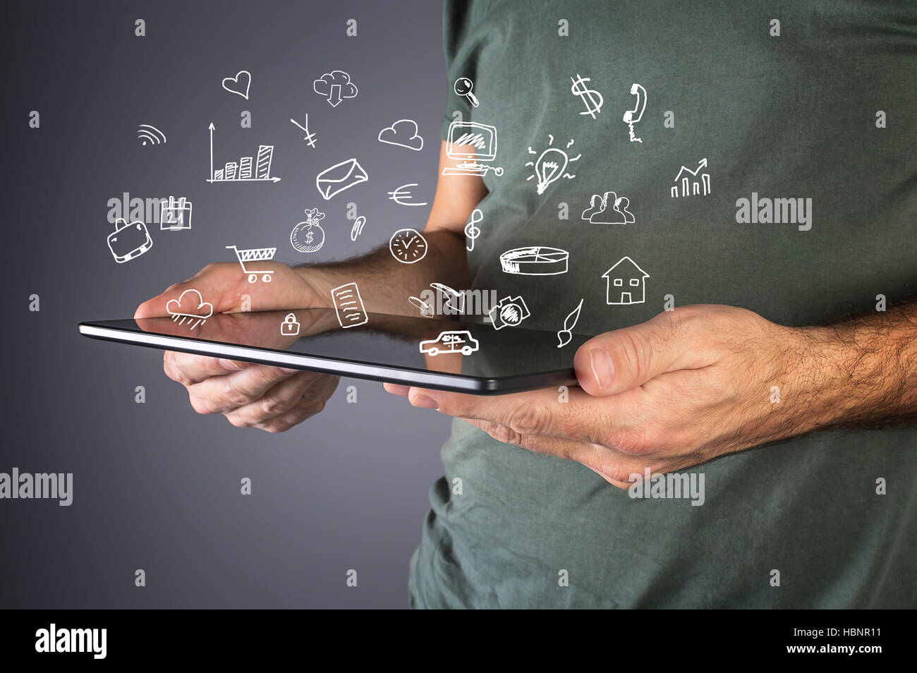 Male hand holding a modern tablet with business icons and symbols. Business, technology, internet and networking concept. Stock Photo