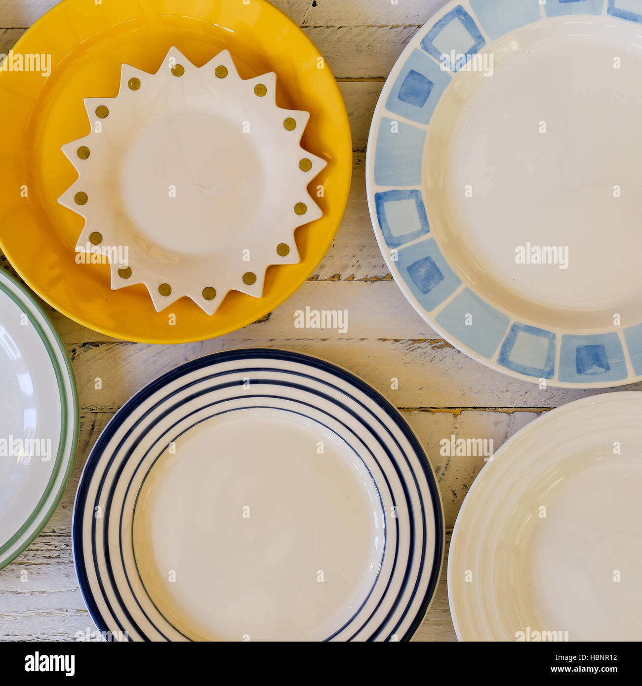 Set of plates with vintage shape border pattern assorted ceramic china on white painted rough wood background Stock Photo