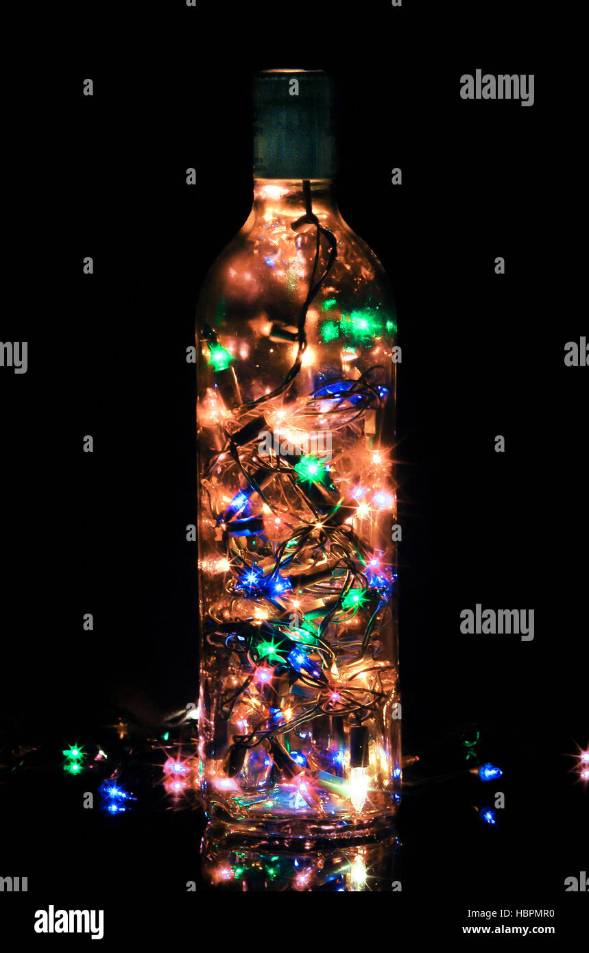 Glass bottle light with christmas yellow orange blue green pink lights over black background Stock Photo
