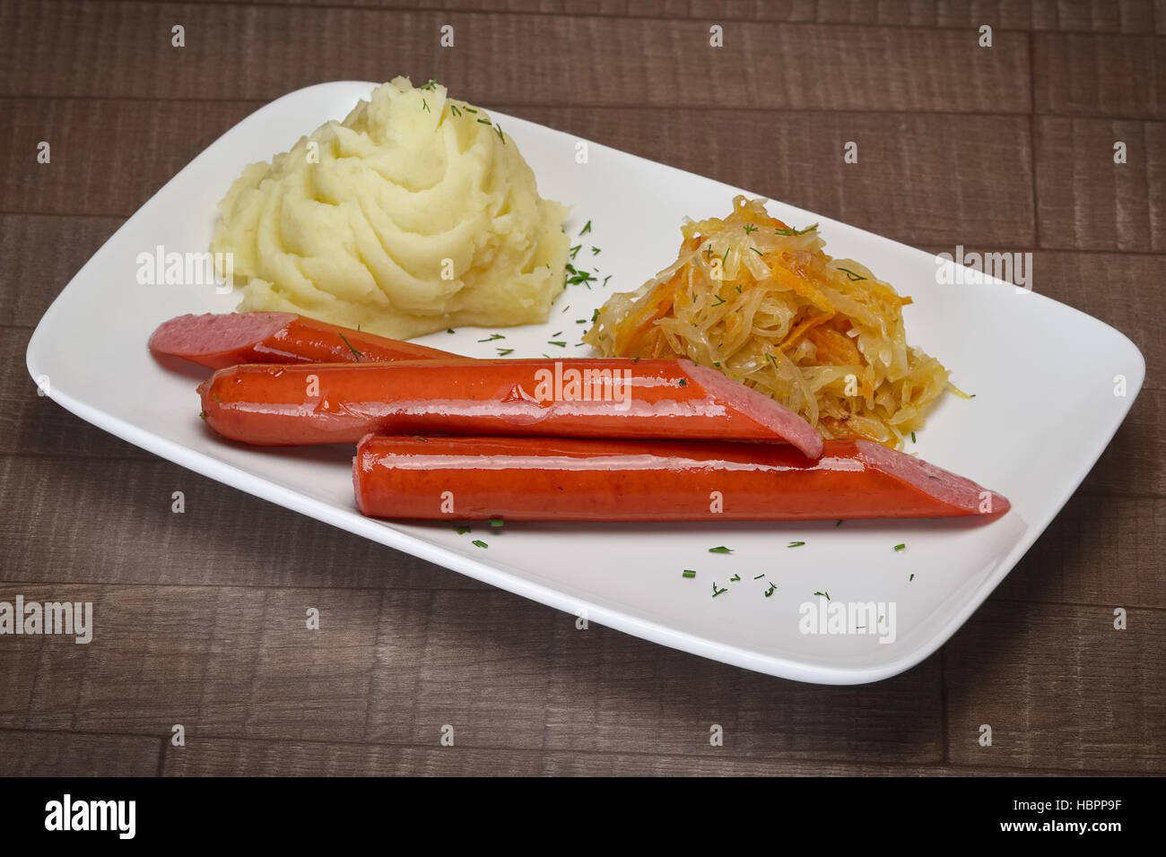 Frankfurter sausage fried cabbage and mashed potato on wooden table Stock Photo