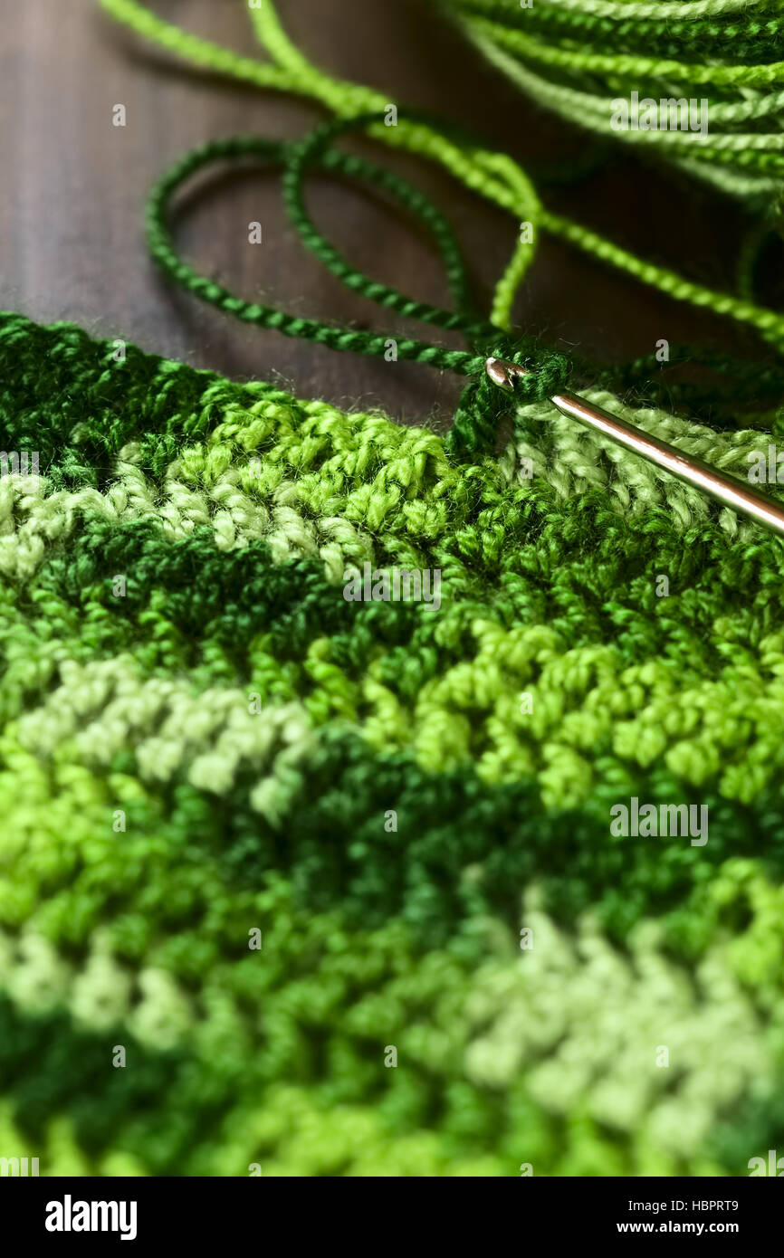 Crochet handicraft, making a place mat out of green yarn with a pattern