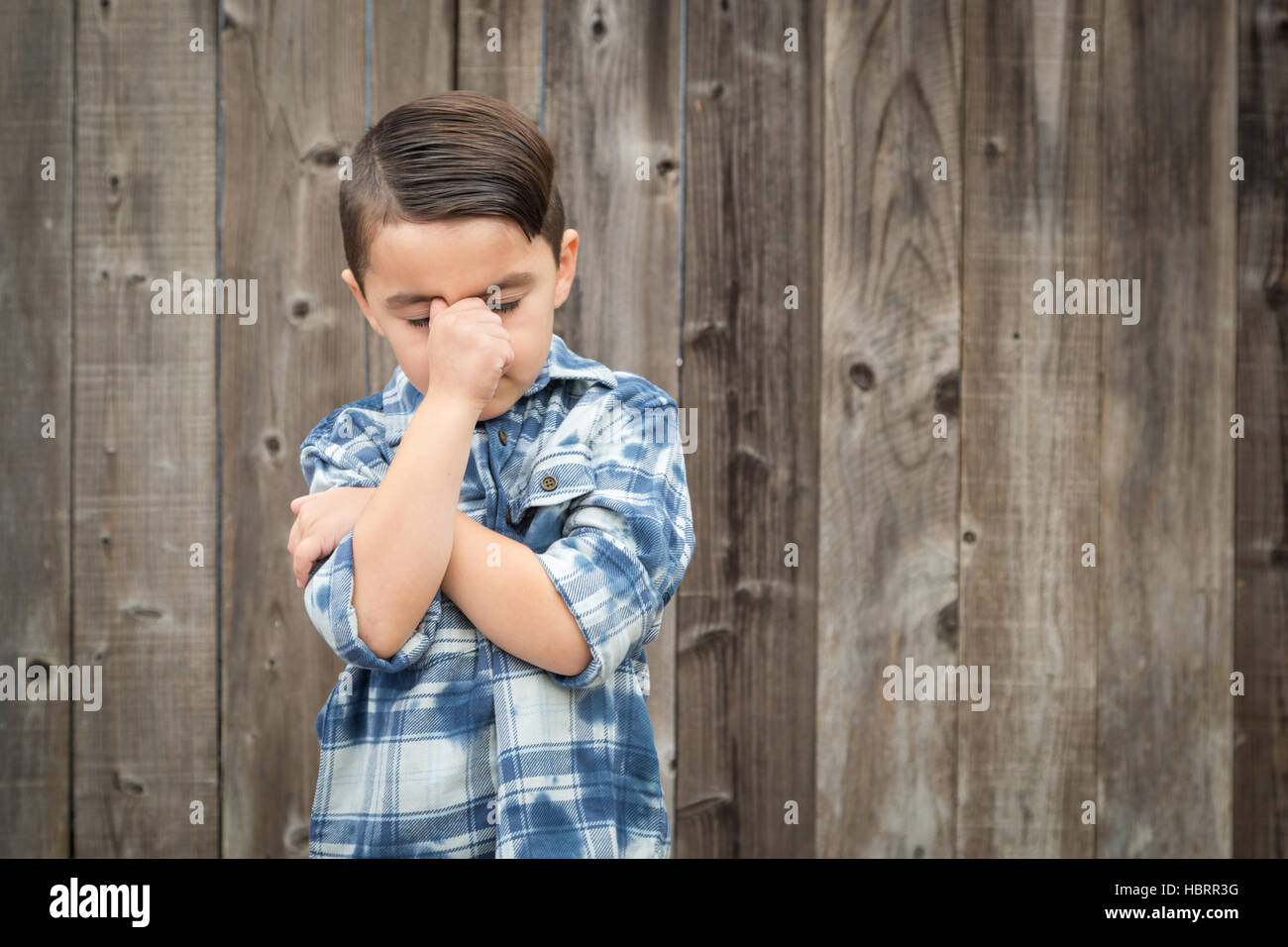 Young Frustrated Mixed Race Boy With Hand on Face Against Wooden Fence. Stock Photo