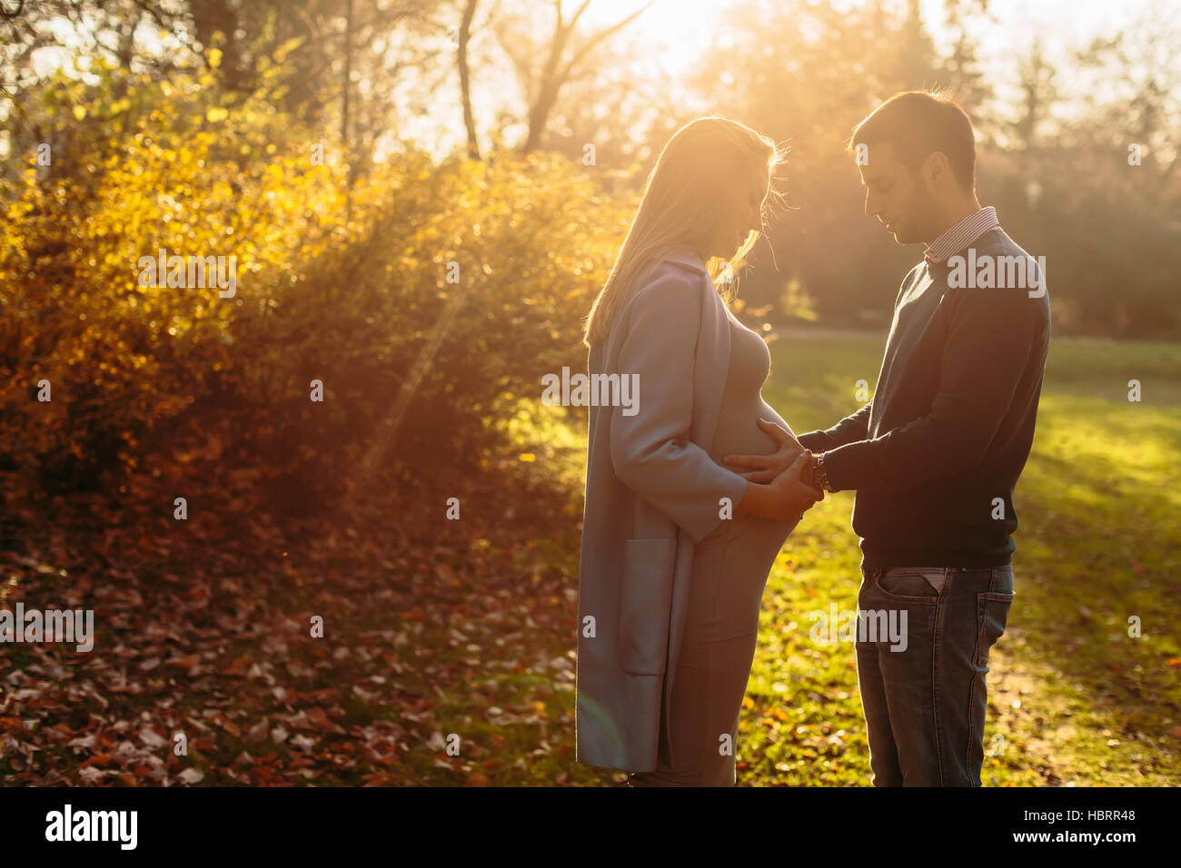 Pregnant woman and man posing at autumn park Stock Photo - Alamy