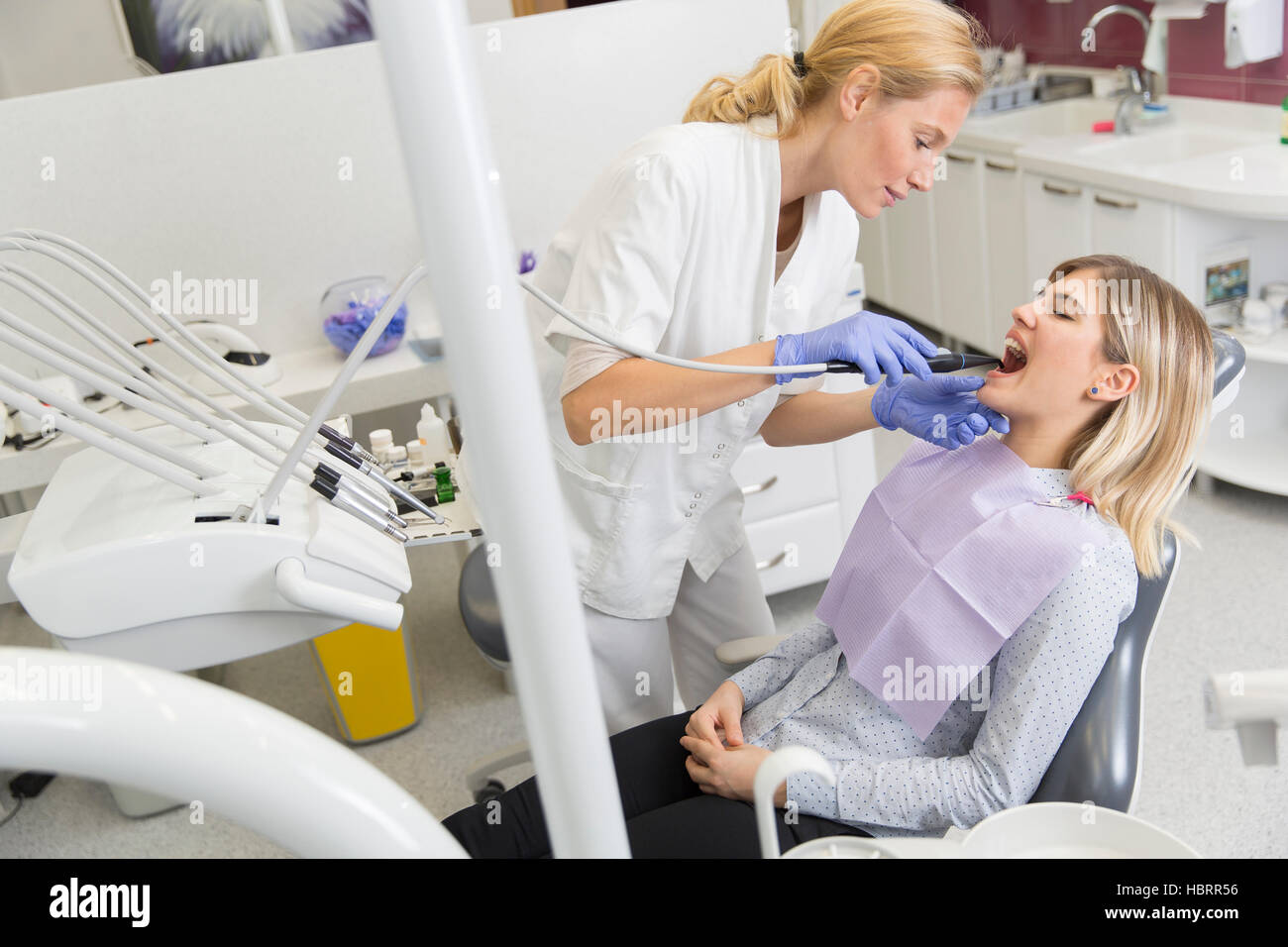 Doctor in uniform checking up female patient's teeth in dental clinic