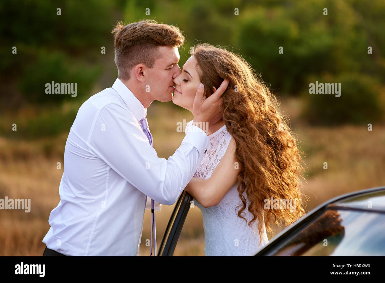 bride and groom kissing near car on wedding walk Stock Photo - Alamy