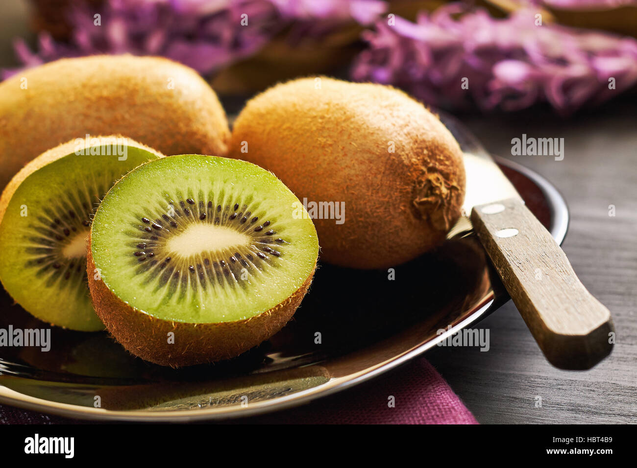 Kiwifruit served on plate on black wooden background Stock Photo