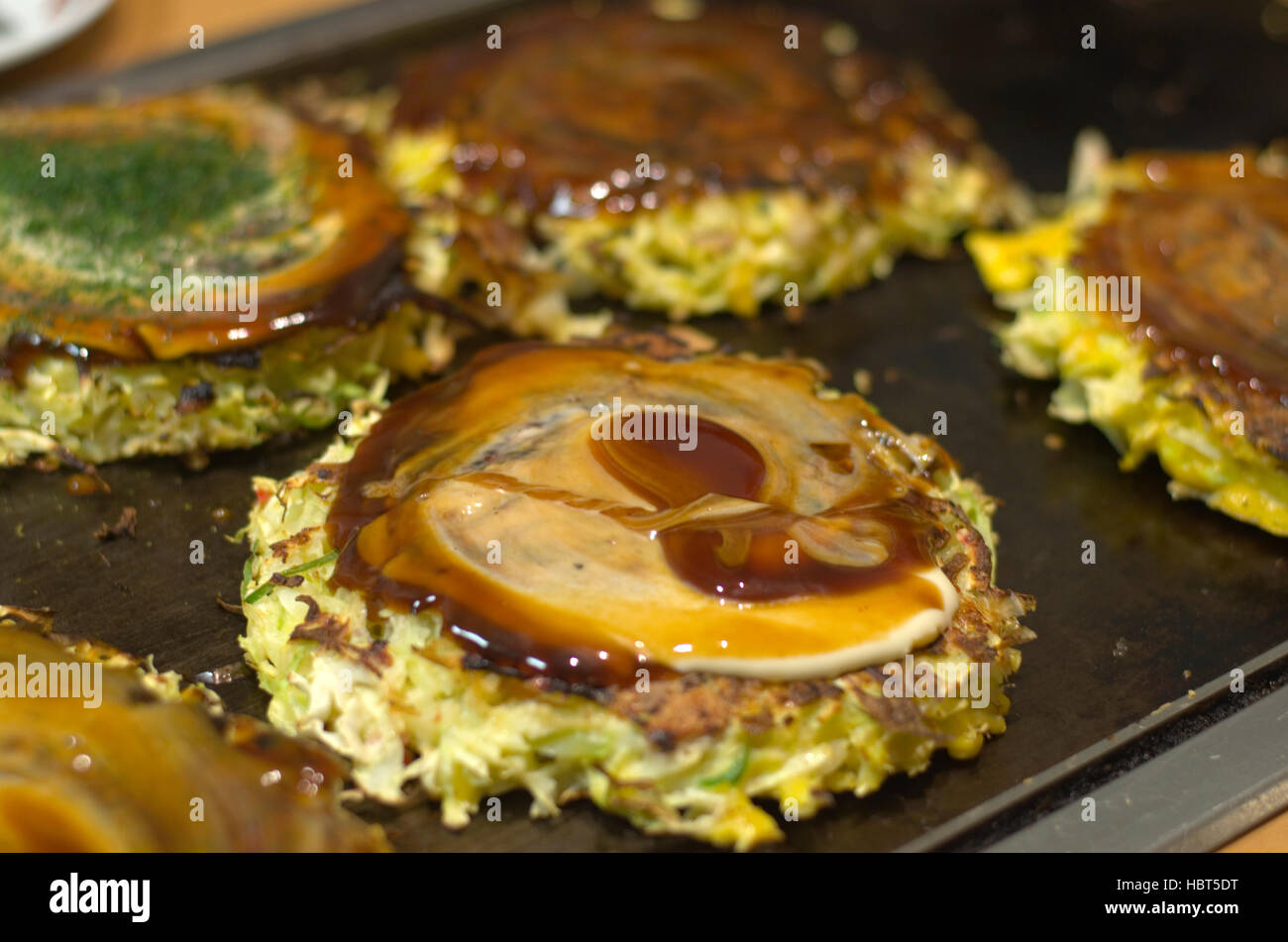 Okonomiyaki cooking on a hot plate. Stock Photo