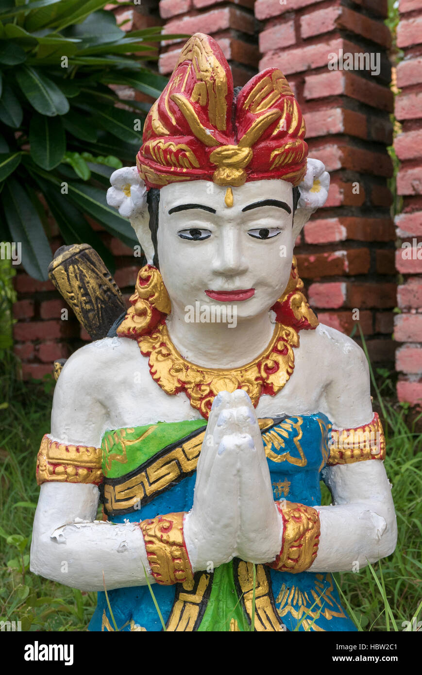 Balinese sculpture with red flower in garden in Lovina, Bali. Indonesia Stock Photo