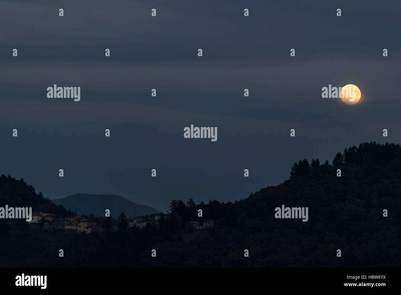 Moon rising over the medieval hilltop town of Barga, in Tuscany, Italy. Stock Photo