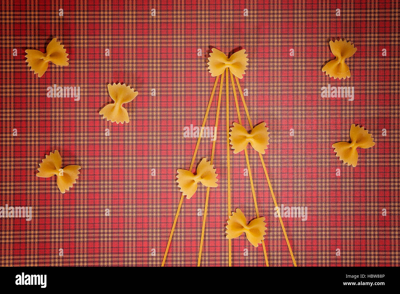 Christmas tree made of spaghetti and bow tie pasta on red squared