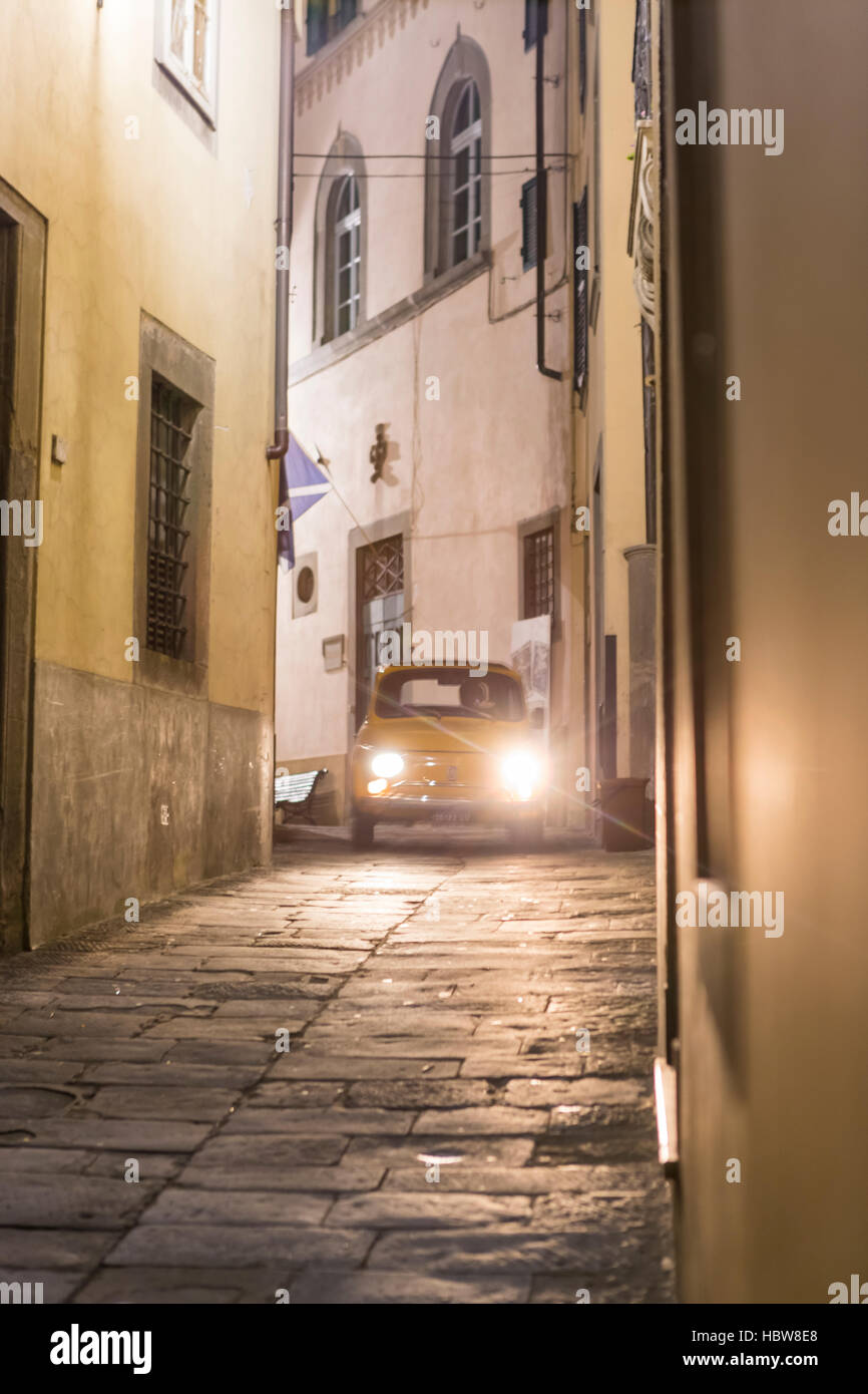 A Fiat CinqueCento negotiates the narrow streets of Barga. The medieval hilltop town of Barga, in Tuscany, Italy. Stock Photo