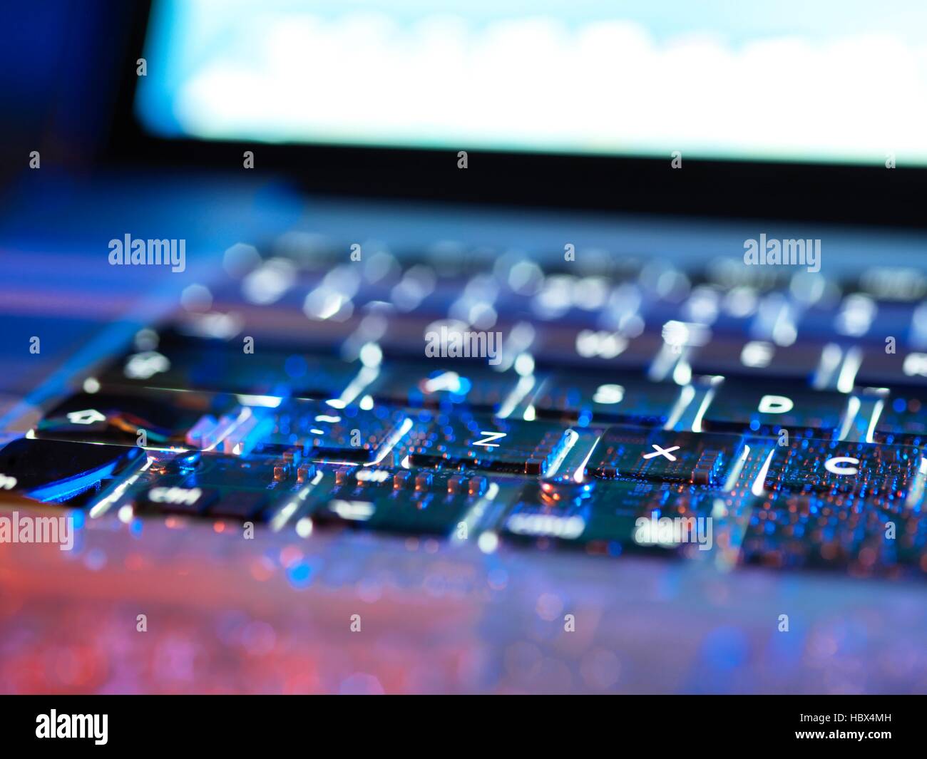 Double exposure of a laptop computer keyboard exposing the electronics underneath. Stock Photo