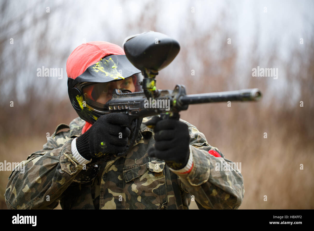 Paintball sport player wearing protective mask and aiming gun Stock Photo